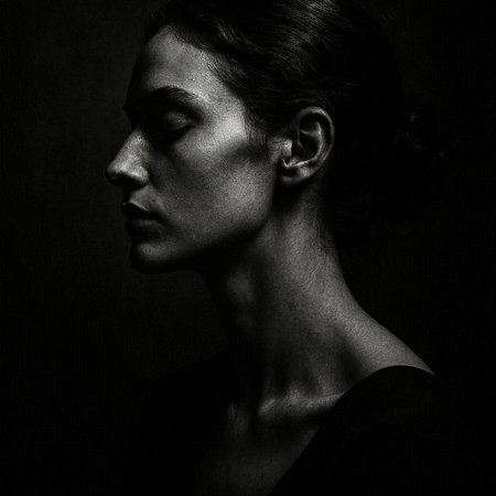 Black and white portrait of a young beautiful woman on dark background.
