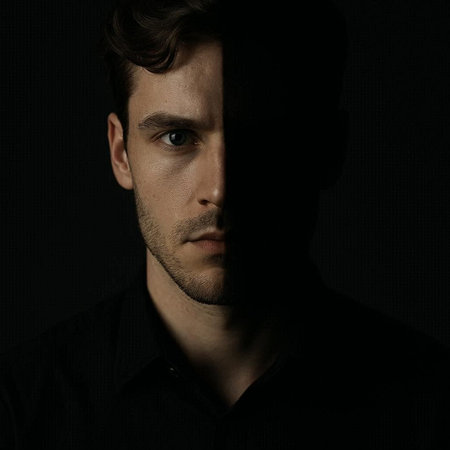 Portrait of a young man in a black shirt on a dark background