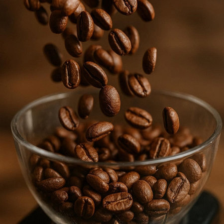 Coffee beans falling in a glass cup on a wooden backgroundの写真素材