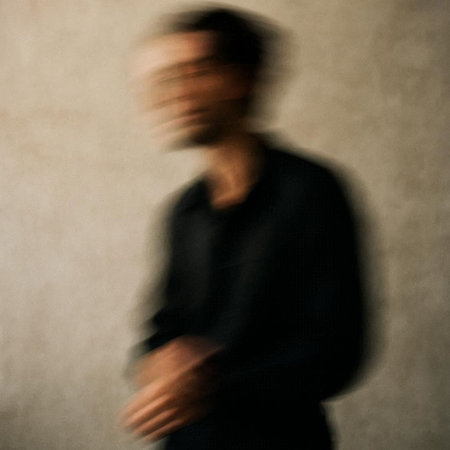 Blurred image of a man in a black jacket on a gray background