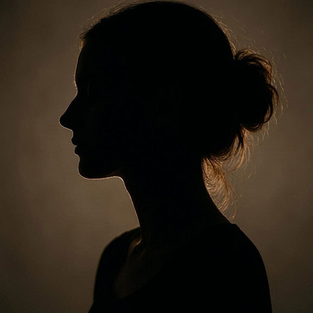 Silhouette of a young woman in profile on a dark background
