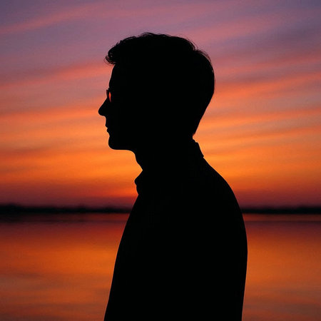 Silhouette of a man on the river bank at sunset.