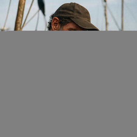 A fisherman with a fishing rod on the boat.の写真素材