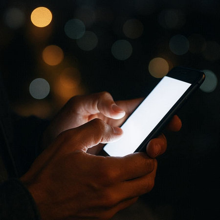 male hands holding a smartphone with a blank screen on a blurred background