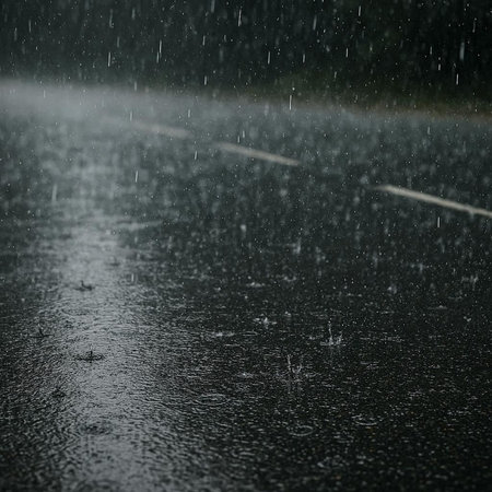 Rain drops on a wet asphalt road during a heavy rainstorm.