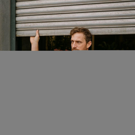 Handsome caucasian man standing in front of a window and smiling