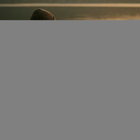 Rear view of a man in a hat looking at the lakeの写真素材