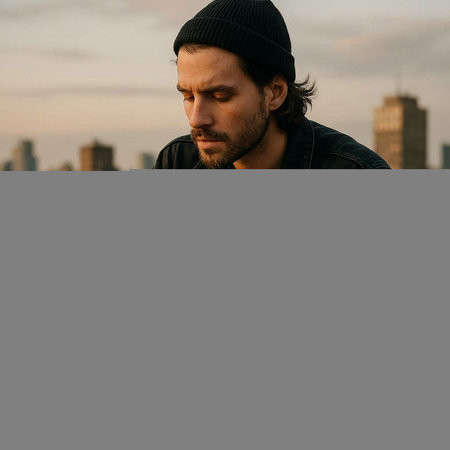 Handsome young man with a beard in a black hat and leather jacket on the background of the city.