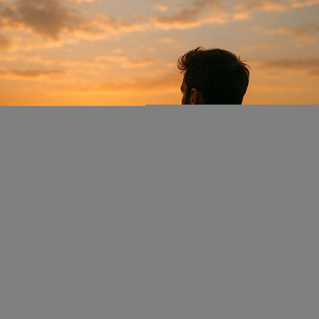 Silhouette of a young man standing on the beach at sunset