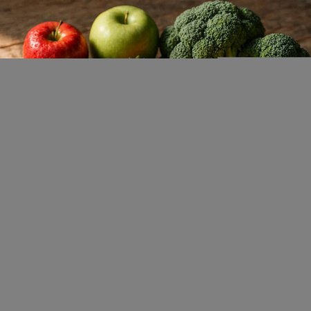 Green apple, red apple, broccoli and red apple on wooden table