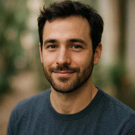 Portrait of a handsome young man with a beard smiling at the camera.