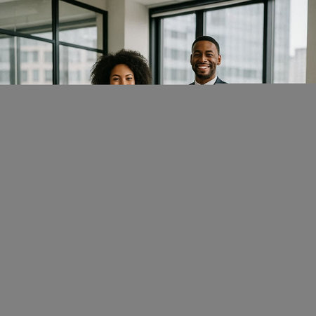 smiling african american businessman and businesswoman looking at camera in officeの写真素材
