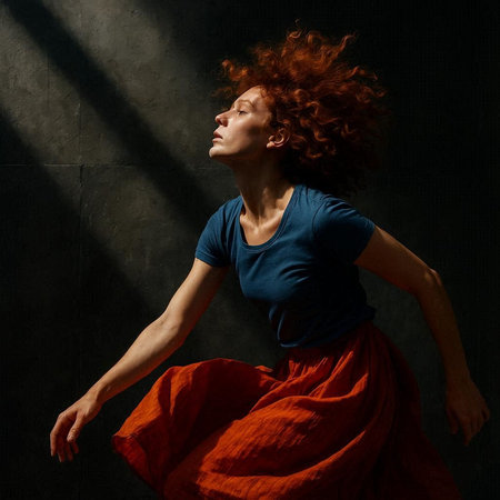Young beautiful woman with red hair dancing on dark background. Studio shot.