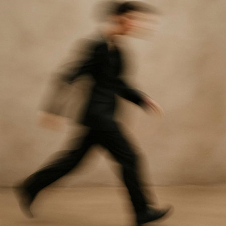 Blurred image of a man in a suit walking in motion.