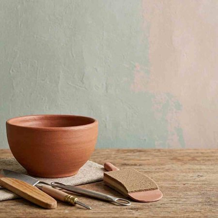 empty clay bowl and kitchen utensils on rustic wooden table