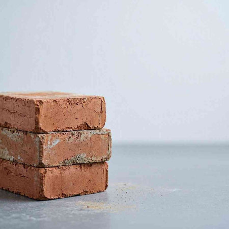 Stack of red bricks on grey background. Copy space for text.