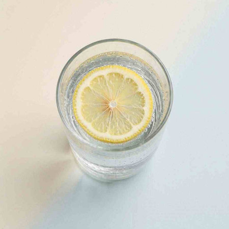 A glass of water with lemon on a white background. Top view.