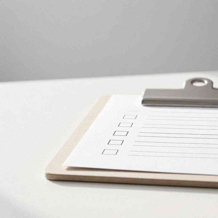 Clipboard with blank paper sheet on white table with copy space