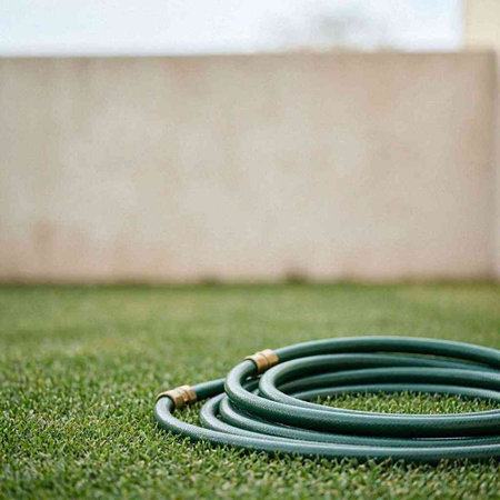 Garden hose on the green grass with copy space. Outdoor background