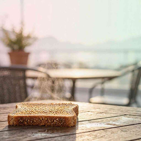 A slice of bread on a wooden table against the background of the sea
