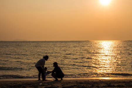 Woman with a baby on hands at sunset on  the beach bangsaen Thailandの写真素材