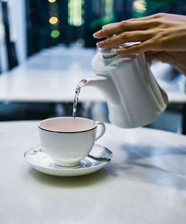 Pouring tea in teapot and cupの写真素材