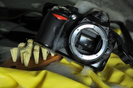 Conceptual image of a camera being cleaned inside and outside with detergent and a scrub brushの写真素材
