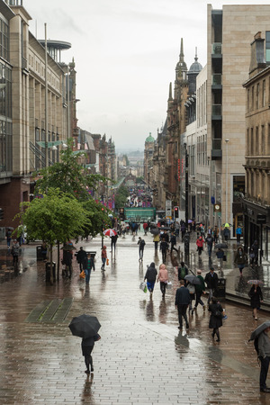 A rainy street view of Buchanan Street in Glasgow with people holding umbrellasのeditorial素材
