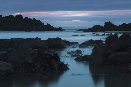 A long exposure of rocks in the water creating a moody mystic seascapeの写真素材