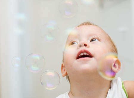 The little boy looks at flying soap bubblesの写真素材