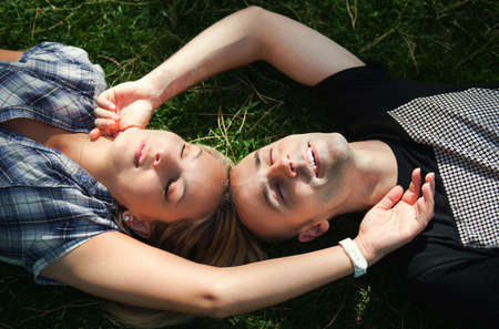 Young couple lying on the grass with eyes closedの写真素材
