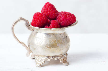 Ripe red raspberries in the old cupの写真素材