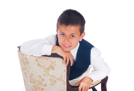 Beautiful smiling boy sitting on a chairの写真素材