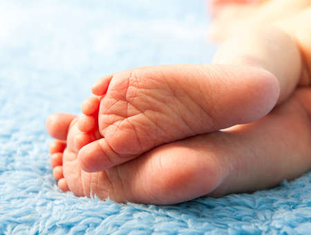 little legs newborn baby on a blue blanketの写真素材