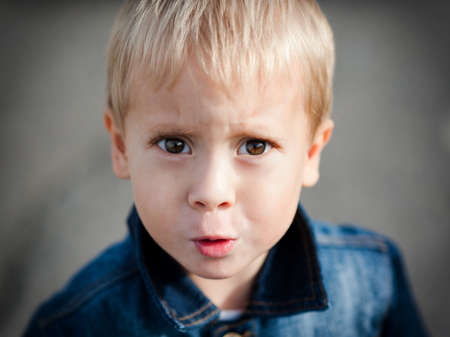 Portrait of the offended little boy on nature
