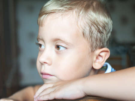 Beautiful cute young boy thinking sitting on chair