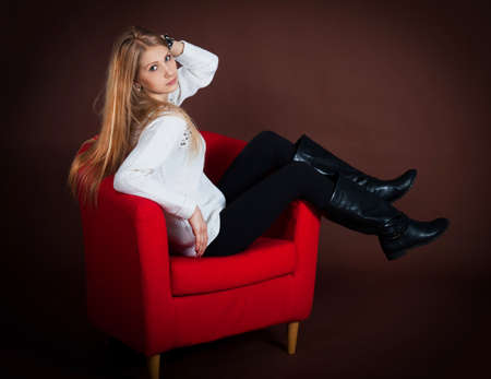 Beautiful young girl sitting on a chairの写真素材