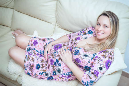 Beautiful pregnant girl lying on the couchの写真素材