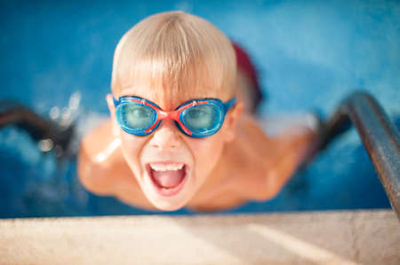 Happy boy in glasses of water swims in the poolの写真素材