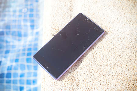 Smartphone around the pool with water dropletsの写真素材