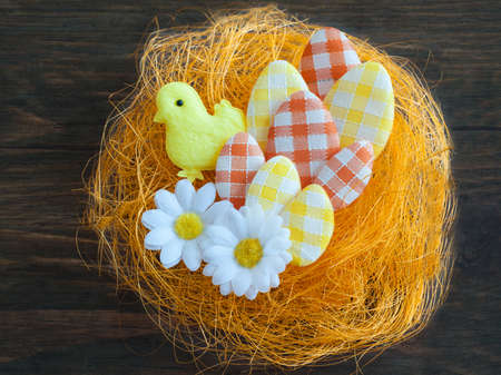 Easter eggs in an artificial nest on a wooden background