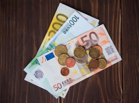 Paper money euro and euro coins on a wooden background