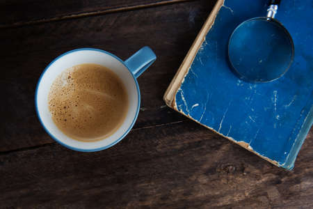 A cup of coffee on the wooden background with the bookの写真素材