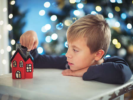 Cute little boy on a Christmas night looking at a small houseの写真素材