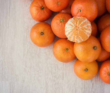 Fresh mandarins and peeled mandarins on a wooden backgroundの写真素材
