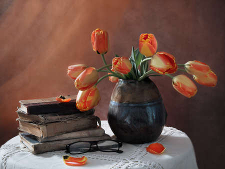 still life with old books and tulips in a dark vaseの写真素材