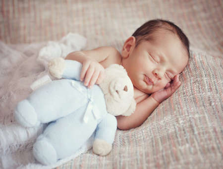little baby is sleeping sweetly with a toy in his hands.の写真素材