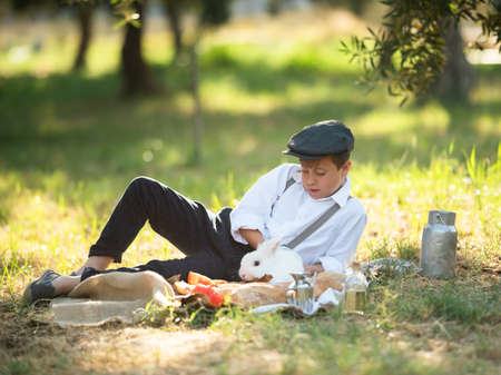 Boy playing with a rabbit in the park on a picnicの写真素材
