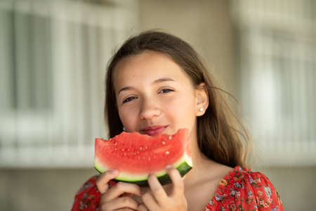 Portrait of a young brunette little girl with watermelon, summer outdoorの写真素材