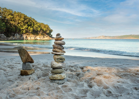 Pyramid stones balance on the sand of the beach. The object is in focus, the background is blurred.の写真素材